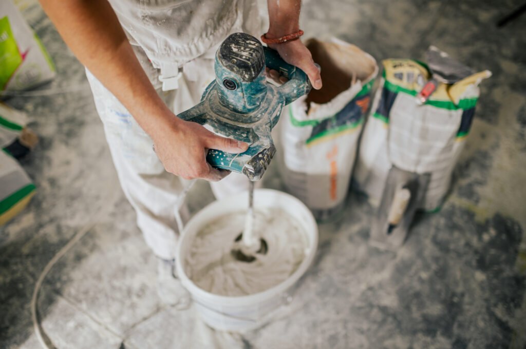 Close up of worker's hands mixing plaster with manual mixer