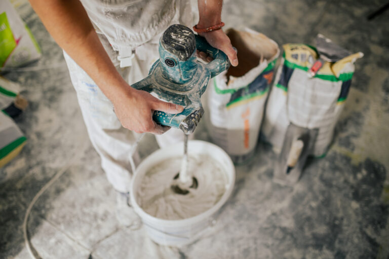 Close up of worker's hands mixing plaster with manual mixer