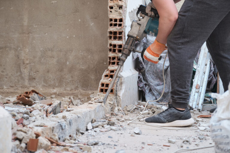 Unrecognizable man using a jackhammer to drill into wall